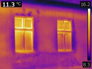 thermal image of the front of a house with heat escaping from windows